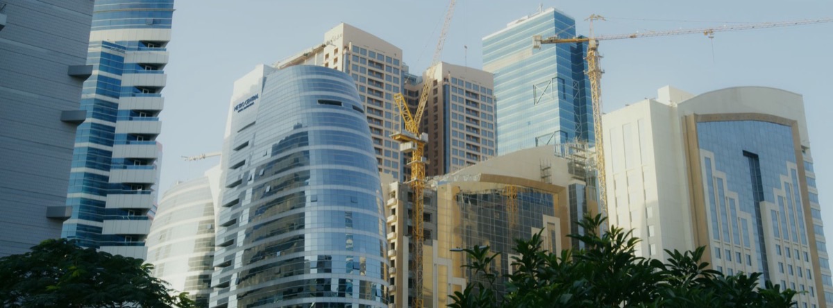 Prédios residenciais e comerciais em construção, com guindastes no meio